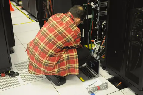 A technician working beside a server rack.