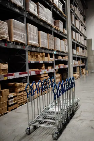 A warehouse aisle with boxes, stock and handling carts.